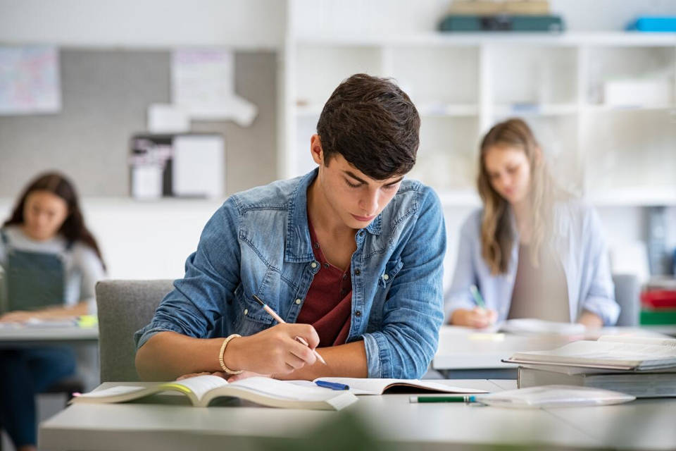 Focused,Young,Man,Taking,Notes,From,Books,For,His,Study.